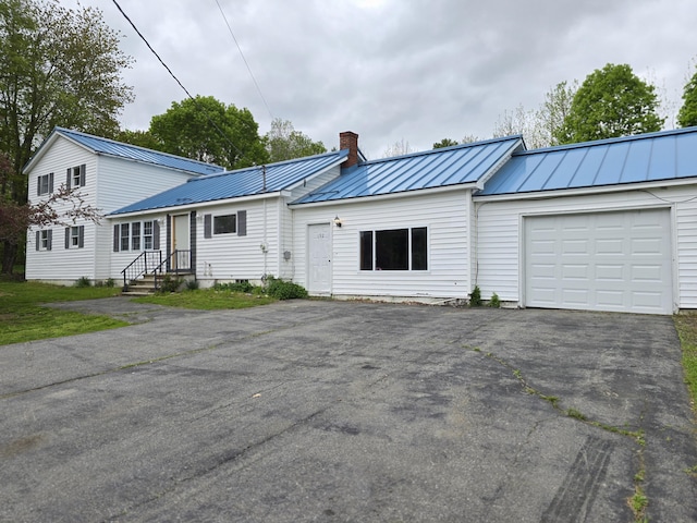 192 Fox Hill Rd, Athens, ME 04912 - view of front facade with a standing seam roof, asphalt driveway, a chimney, an attached garage, and metal roof