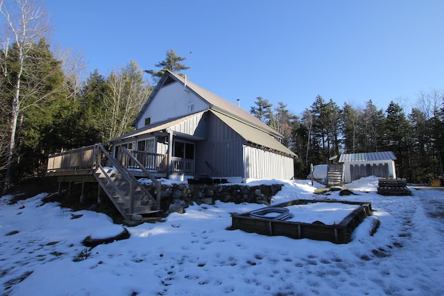 snow covered property with a jacuzzi, a deck, and an outdoor structure