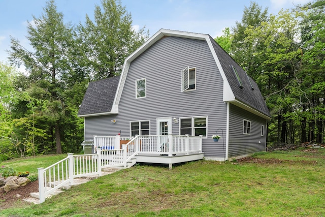 rear view of house with a wooden deck and a lawn