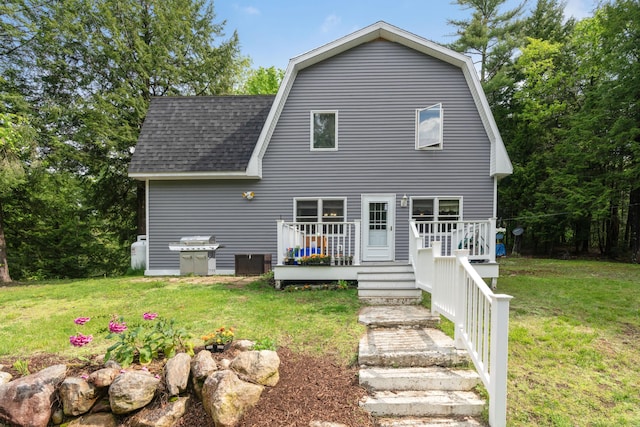 rear view of house featuring a wooden deck and a yard