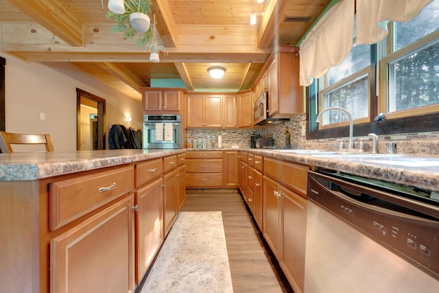 kitchen featuring appliances with stainless steel finishes, beamed ceiling, sink, decorative backsplash, and light wood-type flooring