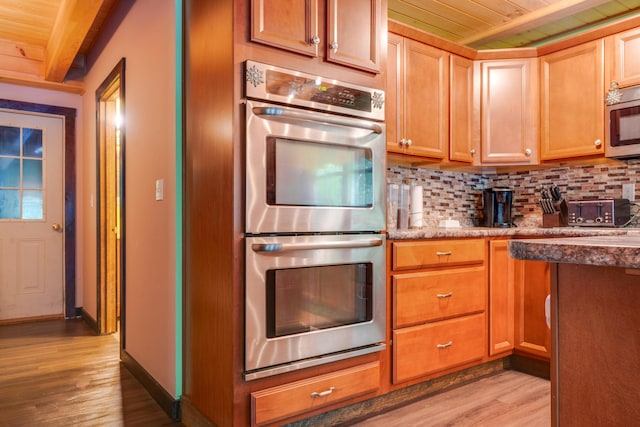 kitchen with appliances with stainless steel finishes, light hardwood / wood-style floors, decorative backsplash, wooden ceiling, and beamed ceiling