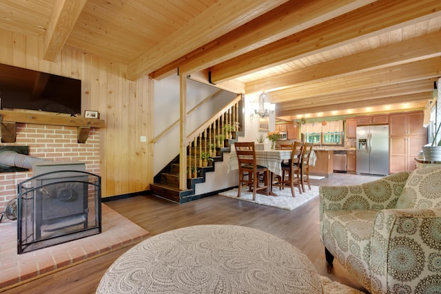 living room featuring wood walls, wood-type flooring, a notable chandelier, wood ceiling, and beam ceiling