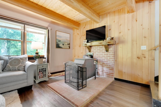 living room featuring beamed ceiling, wood-type flooring, wooden walls, and a wood stove