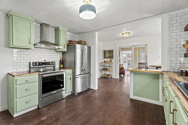 kitchen featuring wall chimney exhaust hood, green cabinetry, appliances with stainless steel finishes, and wooden counters