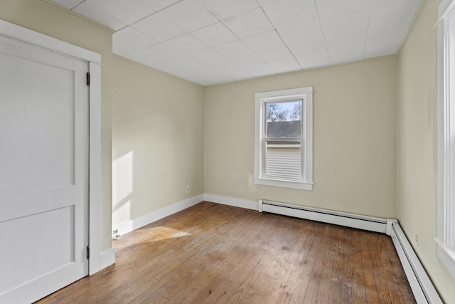 empty room featuring baseboard heating and hardwood / wood-style flooring