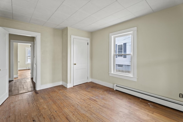 empty room with light hardwood / wood-style flooring and a baseboard heating unit