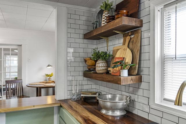 interior space featuring butcher block countertops, decorative backsplash, plenty of natural light, and ornamental molding