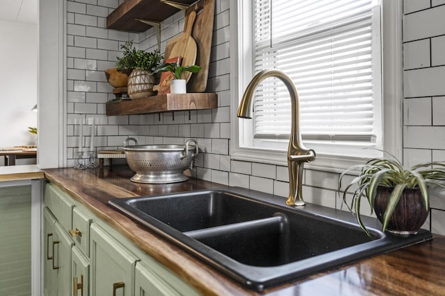 interior details with sink, backsplash, and green cabinetry