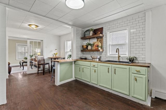 kitchen with green cabinets, sink, a baseboard radiator, and wood counters