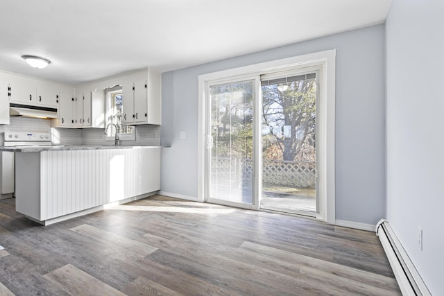 kitchen featuring backsplash, white cabinets, baseboard heating, dark hardwood / wood-style flooring, and kitchen peninsula