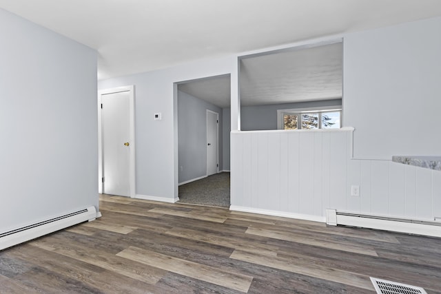 empty room with dark hardwood / wood-style flooring and a baseboard heating unit