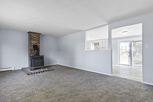 unfurnished living room featuring a wood stove and carpet floors