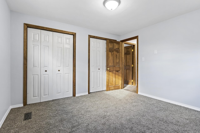 unfurnished bedroom featuring multiple closets and carpet