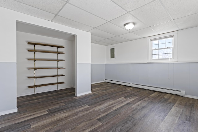 basement with a paneled ceiling, a baseboard radiator, and dark hardwood / wood-style floors