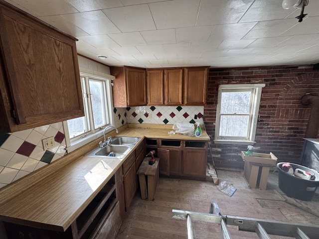 kitchen with backsplash, sink, brick wall, and hardwood / wood-style flooring