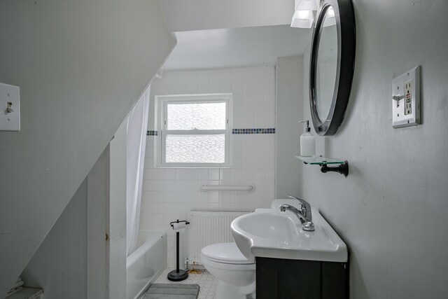 full bathroom with radiator heating unit, toilet, shower / washtub combination, vanity, and tile walls