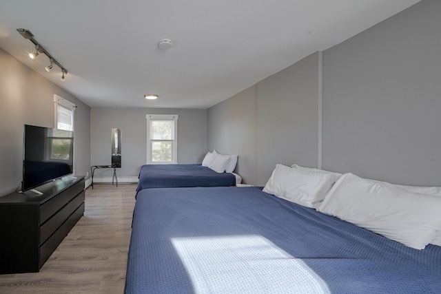 bedroom featuring baseboard heating, rail lighting, and light wood-type flooring