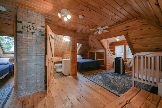 unfurnished bedroom featuring light hardwood / wood-style floors, lofted ceiling with skylight, wooden walls, and wood ceiling