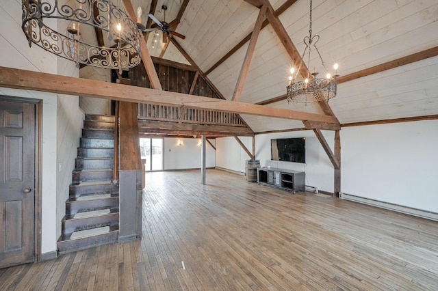 basement featuring baseboard heating, hardwood / wood-style floors, and ceiling fan with notable chandelier