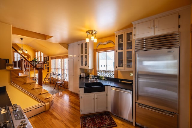 kitchen with white cabinetry, sink, an inviting chandelier, decorative light fixtures, and appliances with stainless steel finishes