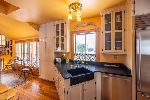 kitchen featuring white cabinetry, sink, light hardwood / wood-style floors, pendant lighting, and appliances with stainless steel finishes