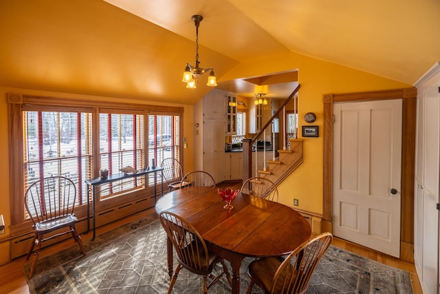 dining area with dark hardwood / wood-style floors, lofted ceiling, and an inviting chandelier