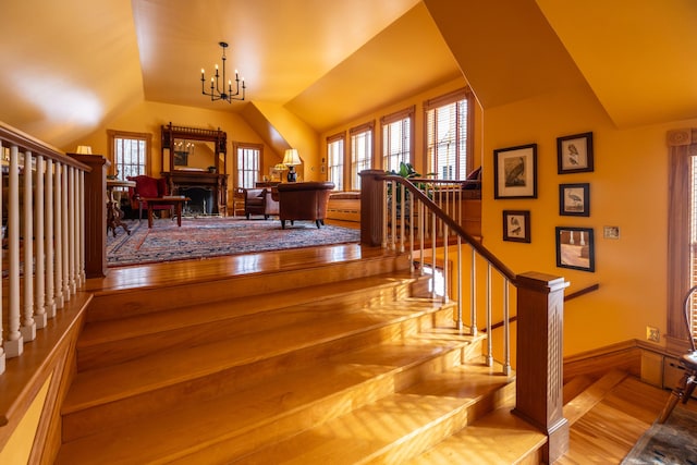 staircase featuring hardwood / wood-style flooring, vaulted ceiling, and an inviting chandelier