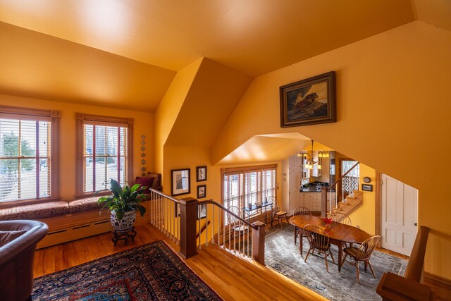 interior space featuring an inviting chandelier, a baseboard radiator, vaulted ceiling, and hardwood / wood-style flooring