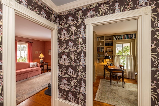 interior space with built in shelves, a wealth of natural light, ornamental molding, and hardwood / wood-style flooring