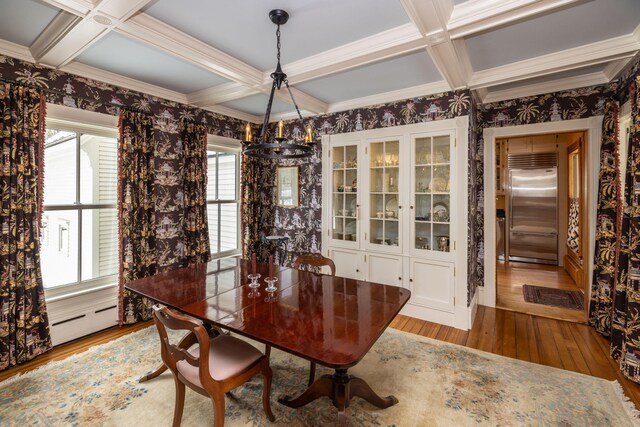 dining space featuring baseboard heating, light hardwood / wood-style flooring, beamed ceiling, and coffered ceiling