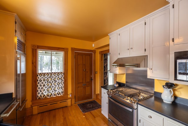 kitchen featuring white cabinetry, stainless steel appliances, extractor fan, and a baseboard heating unit