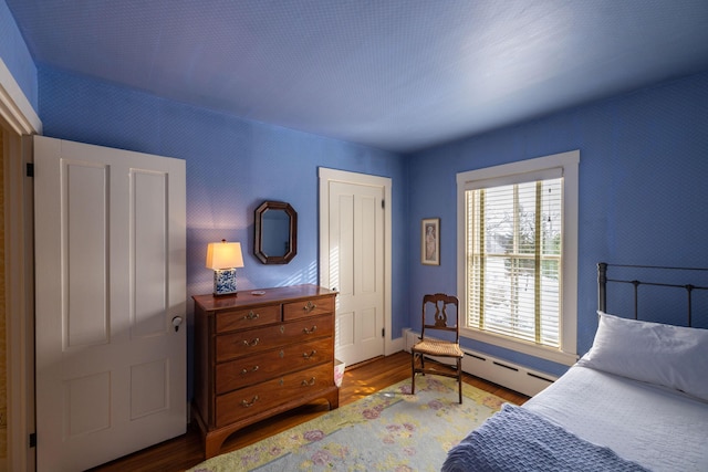 bedroom with a baseboard heating unit and hardwood / wood-style flooring