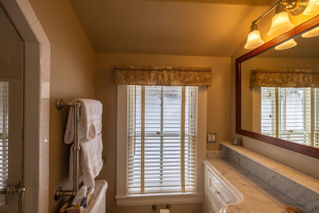 bathroom with plenty of natural light, vanity, and vaulted ceiling