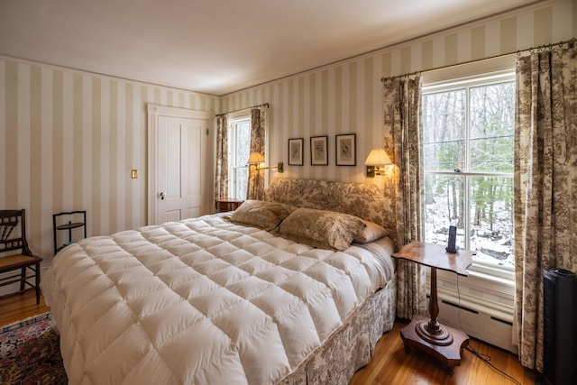 bedroom with multiple windows, a closet, and light hardwood / wood-style flooring