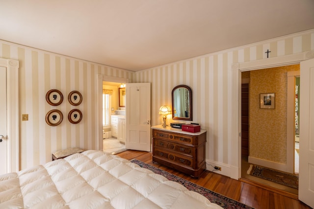 bedroom featuring ensuite bathroom, ornamental molding, and hardwood / wood-style flooring