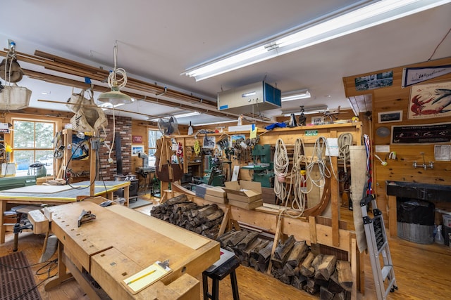 misc room featuring a workshop area, wooden walls, and wood-type flooring