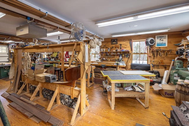 misc room with a workshop area, light hardwood / wood-style flooring, and wood walls