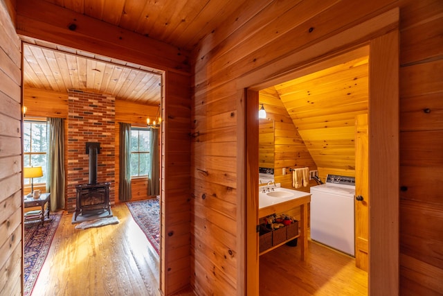 hall with wood ceiling, wood walls, light wood-type flooring, and washer / dryer