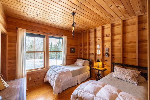 bedroom with wooden walls, wooden ceiling, and light wood-type flooring