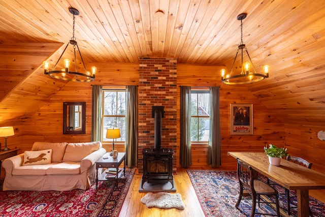 living room featuring a wood stove, hardwood / wood-style floors, a healthy amount of sunlight, and a notable chandelier