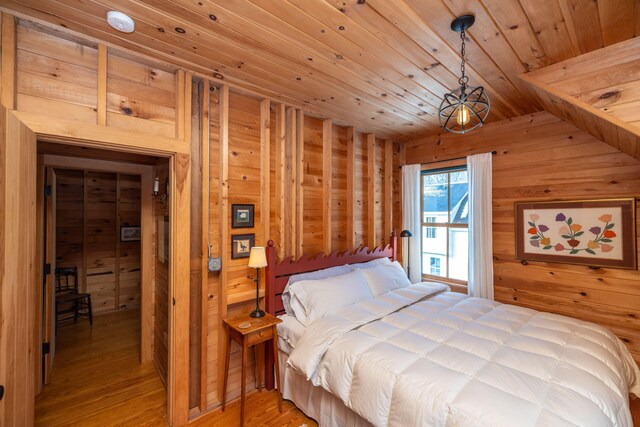 bedroom featuring wooden walls, wooden ceiling, and light wood-type flooring