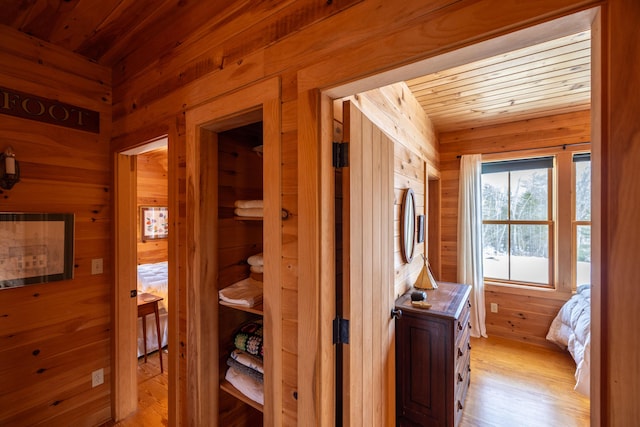 hallway featuring light hardwood / wood-style flooring, wooden walls, and wood ceiling