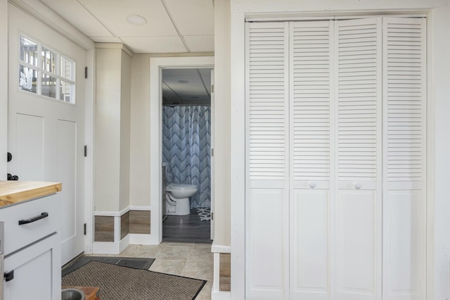 bathroom featuring a paneled ceiling, tile patterned flooring, and toilet