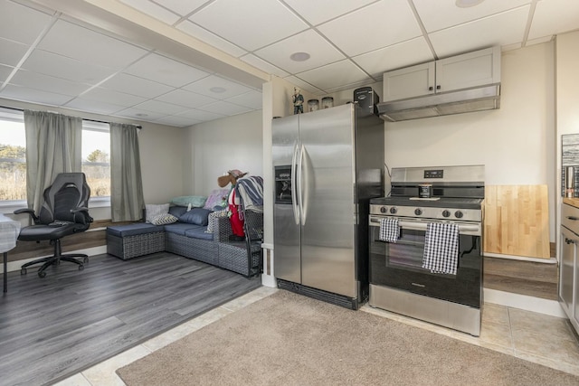 kitchen with a paneled ceiling, light tile patterned floors, and stainless steel appliances