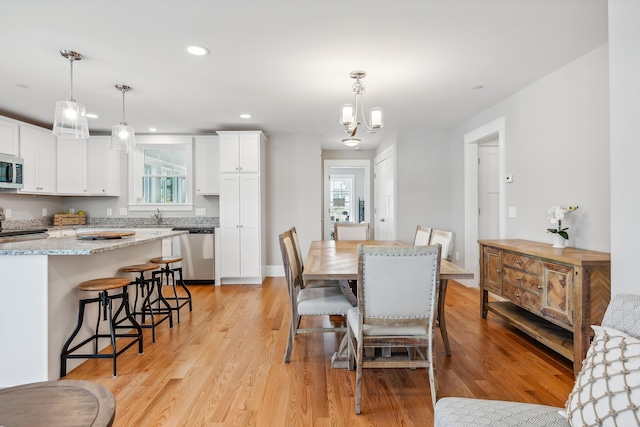 dining space featuring light hardwood / wood-style floors, an inviting chandelier, a wealth of natural light, and sink