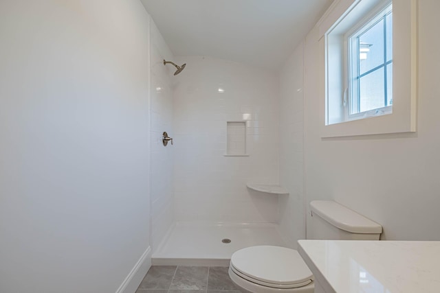 bathroom with tiled shower, vanity, and toilet