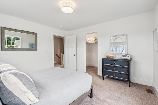 carpeted bedroom featuring a walk in closet, multiple windows, and a closet