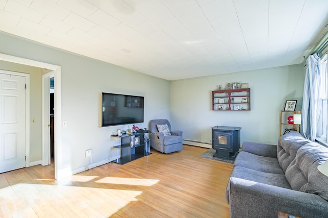 living room with a wood stove, wood-type flooring, and a baseboard radiator