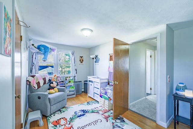 recreation room with a textured ceiling and light hardwood / wood-style floors